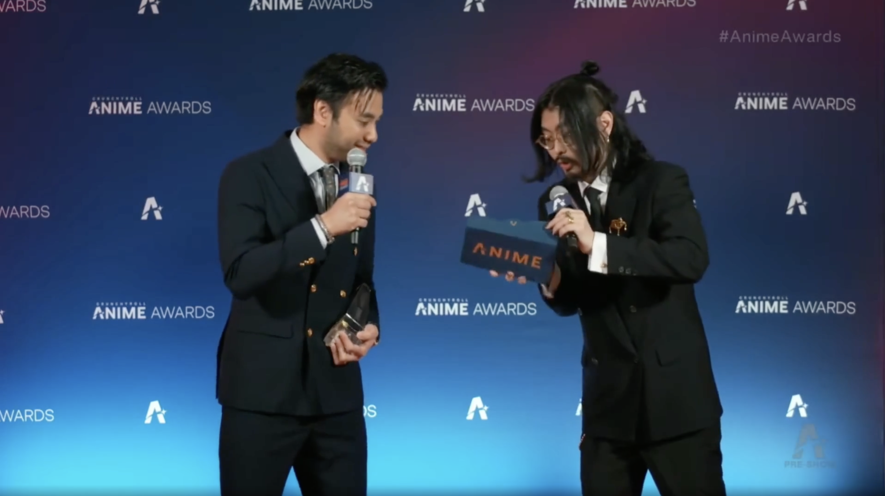 Anime Awards hosts backstage with an award trophy